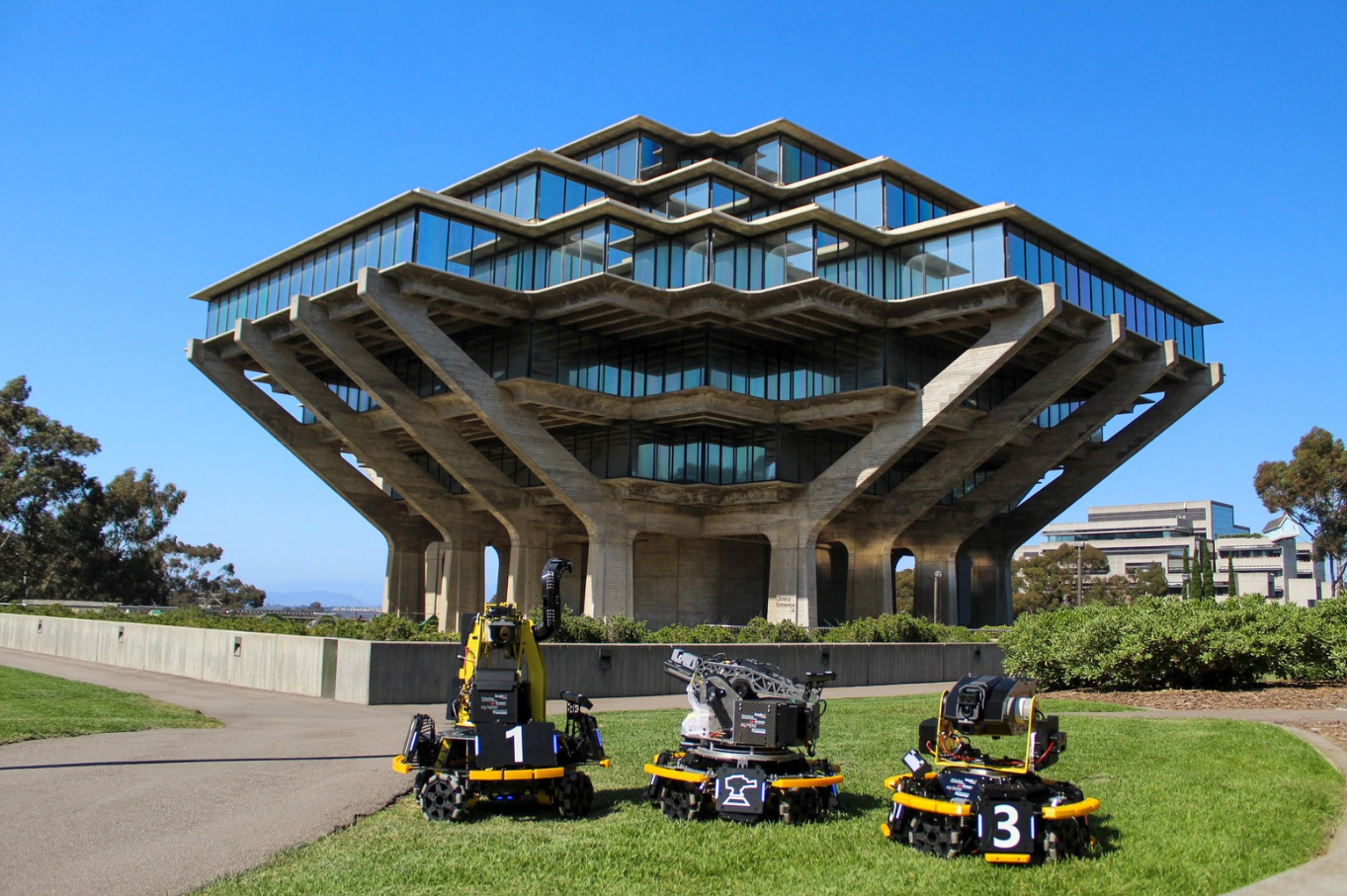 Three Triton Robotics robots posed in front of UC San Diego's Geisel Library