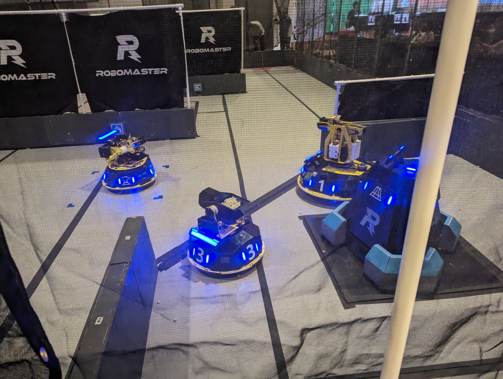 RoboMaster robots illuminated in blue on a competition field