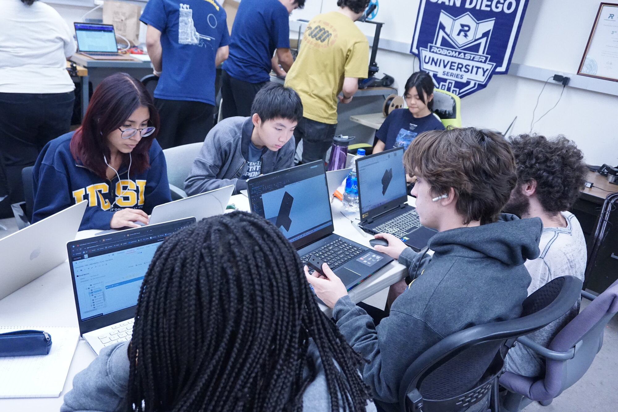 Triton Robotics members designing robot parts on their laptops